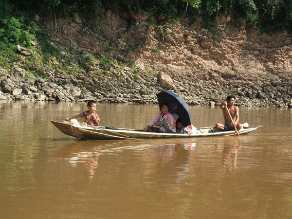 A family on a wooden paddle boat on the Mekong river