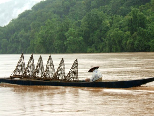 A Lao fisherman in the rain, on Mekong river